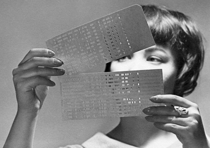 A woman looking at computer punch cards